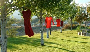 Red dresses hanging from trees outdoors 