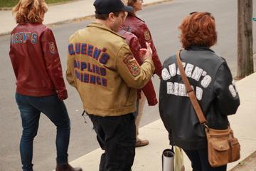 three people wearing Queen's jackets walking on campus