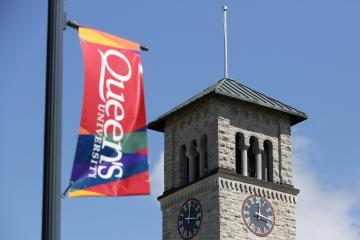 Image of the Queen's flag flying with the Grant Hall clocktower in the background