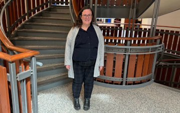 Katelyn Couch standing in front of the spiral staircase in Stauffer Library 